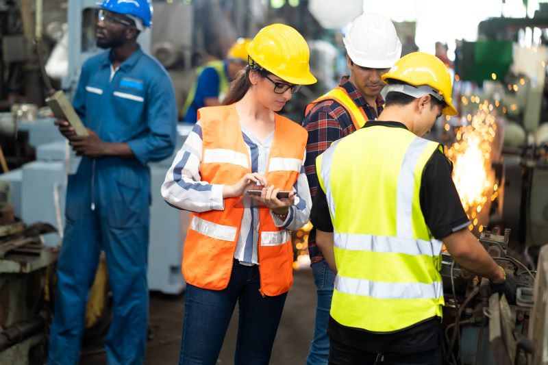 Trabalhador utilizando equipamentos de segurança para trabalho em altura se apoia em vigas de metal.