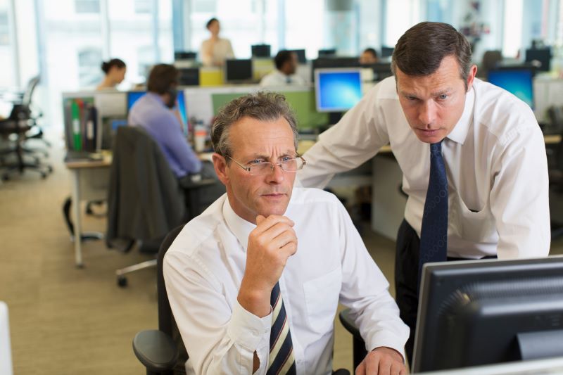 compliance trabalhista​: gestores sérios vendo informações em computador no escritório